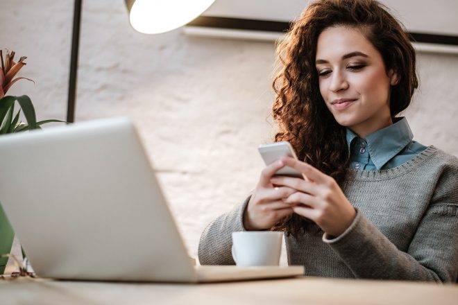 Frau mit Smartphone und Laptop
