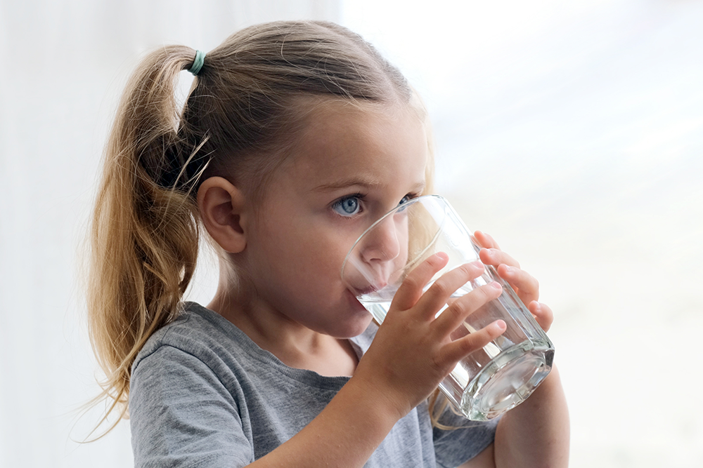 Mädchen trinkt aus einem Glas Wasser