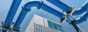 Blaue Wasserrohre im Vordergrund, im Hintergrund ein Gebäude